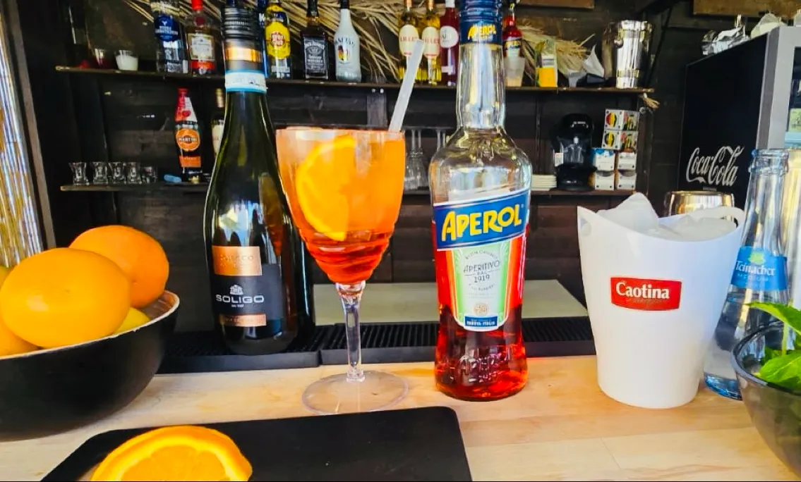 Ein Aperol Spritz wird an der Holztheke frisch zubereitet