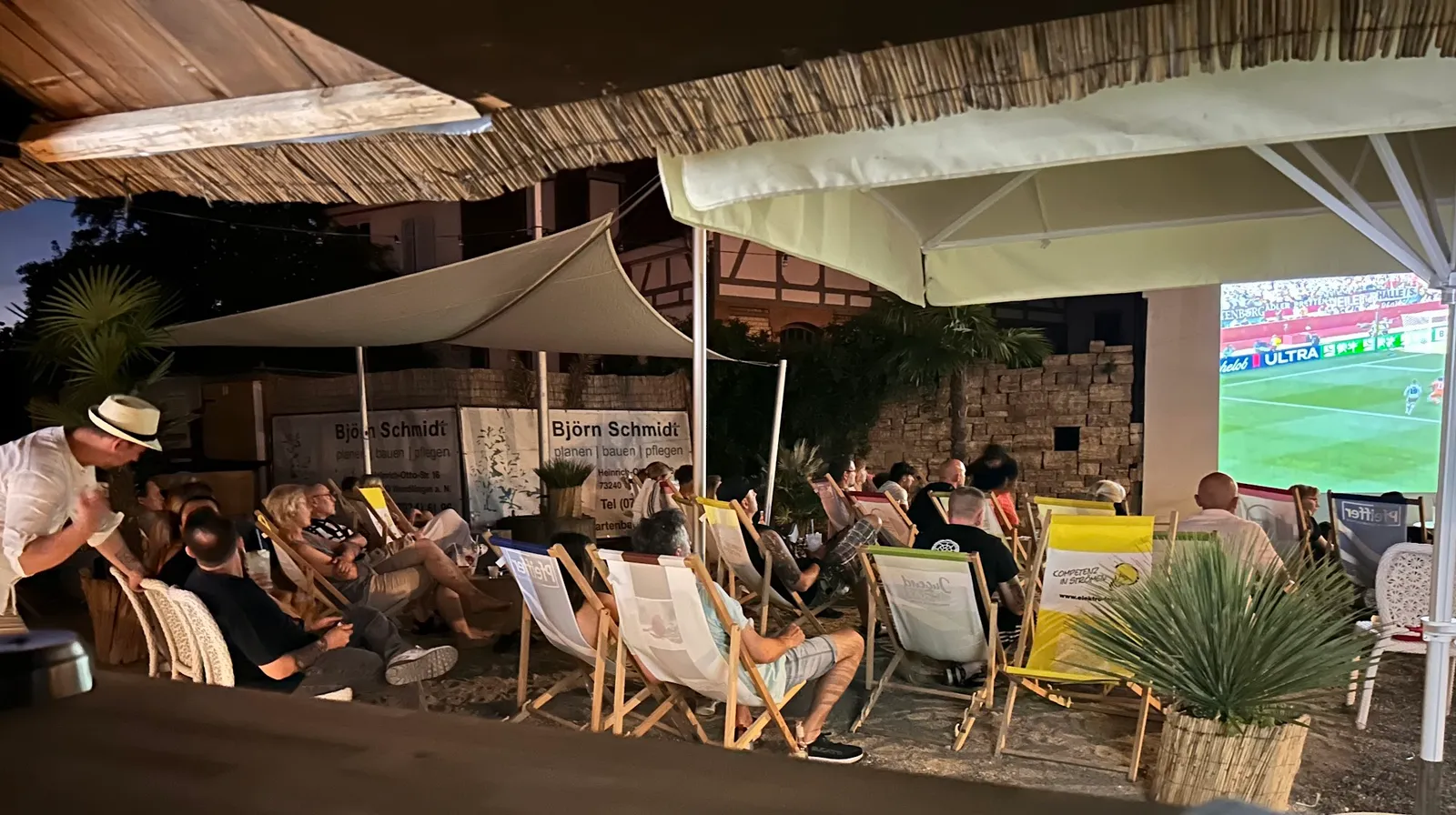 Abendliche Terrasse mit Liegestühlen und Großleinwand beim Public Viewing